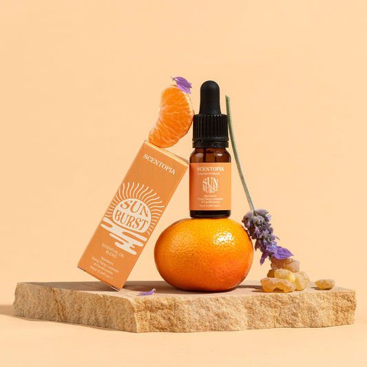 Still life Scentopia Sunburst essential oil  bottle with manadrin, lavender frankincense on orange background