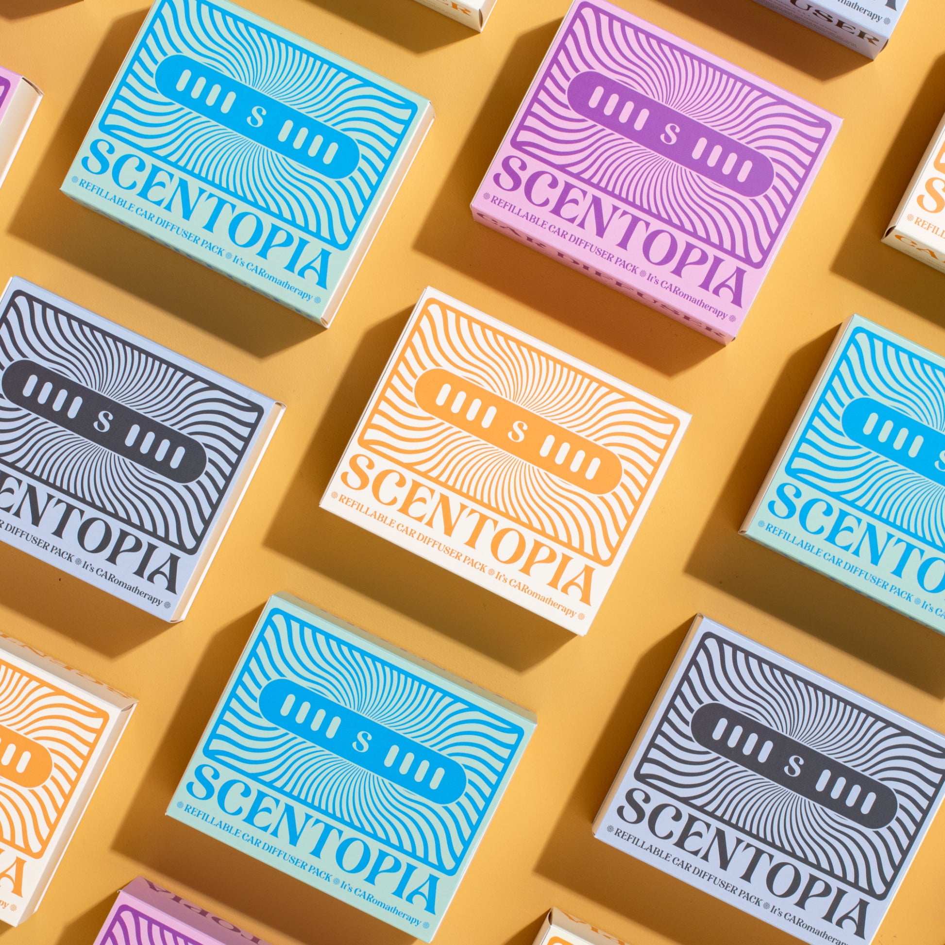 Pattern of Scentopia  car diffuser boxes on a yellow background