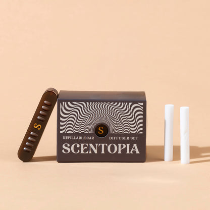 Scentopia refillable car diffuser set with a dark brown box featuring a black and white wavy pattern, a brown diffuser device with a gold 'S' logo, and two white cartridges on a beige background.