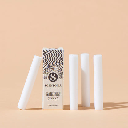 A 4-pack of Scentopia car diffuser refill rods, with one rod lying on its side and three standing upright next to the product box, set against a solid peach background.